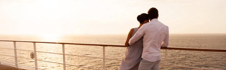 Couple leaning against a ship's railing overlooking the sea and enjoying a cruise similar to a Love Like You Mean It® marriage cruise